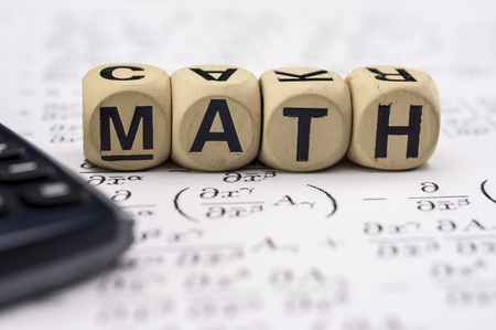 Close up shot of scientific calculator and mathematical equations sheets. Wooden letter blocks assemble the word mathematicsの写真素材