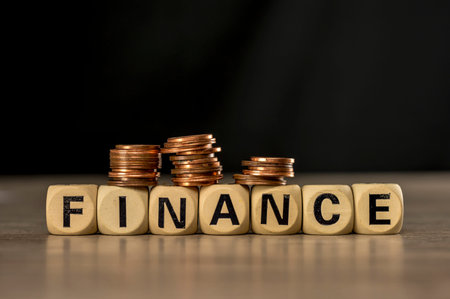 Coin stacks on letter blocks assembling the word finance close up