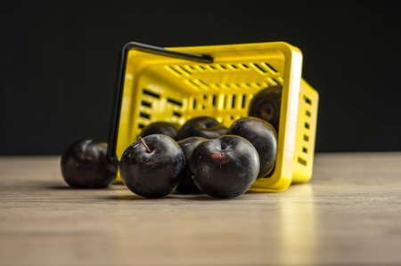 Close up shot of a yellow supermarket basket filled with plumsの写真素材