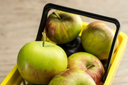 Close up shot of a yellow supermarket basket filled with applesの写真素材