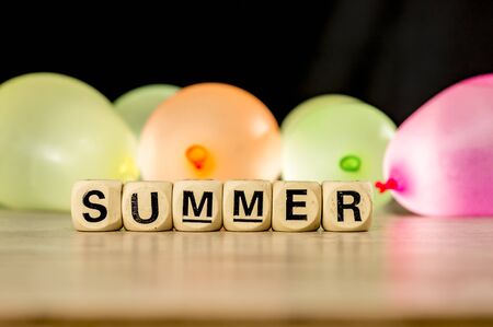 Word summer made of wooden tiles and water balloonsの写真素材
