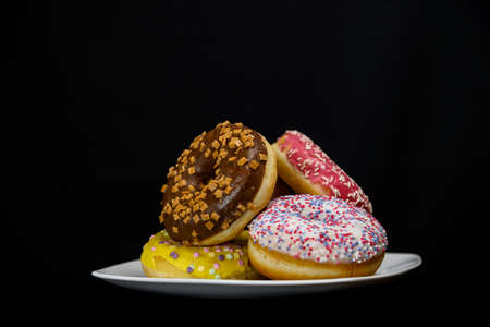 Donuts of different colors in plate close upの写真素材