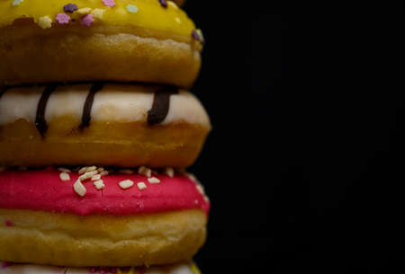 Donuts of multiple colors piled up close upの写真素材