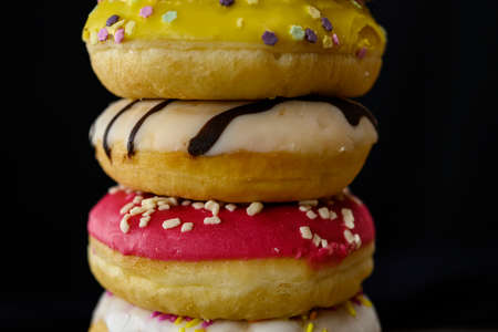 Donuts of multiple colors piled up close upの写真素材