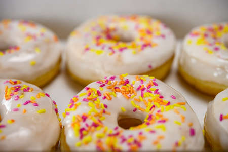 Box of delicious white donuts with sprinklesの写真素材