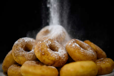 Hand sprinkling donuts with sugar close upの写真素材