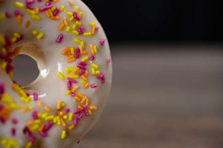 Delicious white donut with colorful sprinkles on tableの写真素材