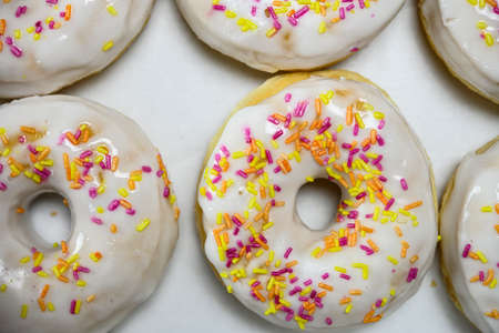 Box of delicious white donuts with sprinklesの写真素材