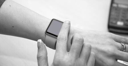 Girl using her iWatch. Close up of a finger about to swipe across a smartwatch.のeditorial素材