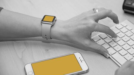 Support staff typing on keyboard. Shot also shows iWatch and iPhone.のeditorial素材