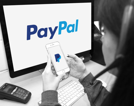 Member of staff using PayPal website and smartphone app to provide customers with support