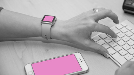 Support staff typing on keyboard. Shot also shows iWatch and iPhone.