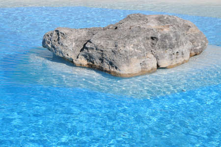 a rock in a crystal clear blue lagoonの写真素材