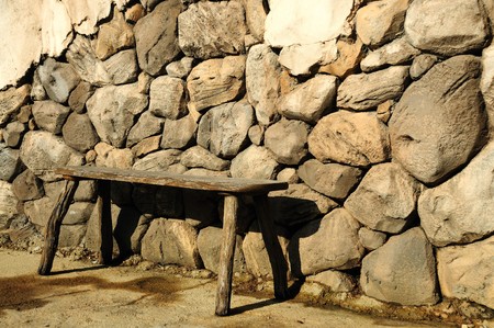 old wood bench up against a rock wallの写真素材