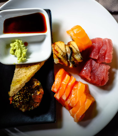 assorted sashimi and sushi served on a white plate with soja and wasabi sauce.の写真素材