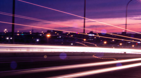 A creative digital illustration depicting High quality design of blurred city light streaks in twilight background, motion glow effects, horizontal bokeh trails, urban night energy, violet urban hues. This AI-generated artwork features unique visual elements suitable for various commercial and editorial applications. AI-generated illustration.の素材