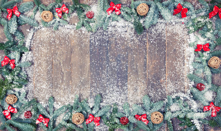 an old wooden background, decorated with pine branches, red loops and snow, a Christmas background