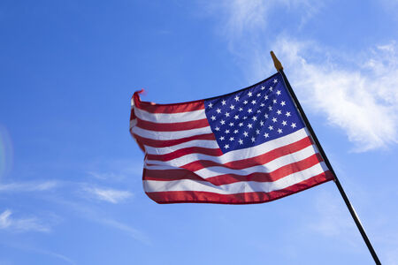 the American national flag in the wind against a blue sky in summerの写真素材