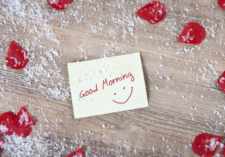 A wooden background with snowflakes and  roses flowers. in the middle a note with the text good morningの写真素材
