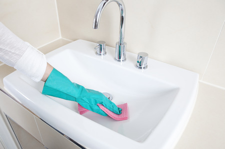 Hands with gloves clean a sink with a clothの写真素材