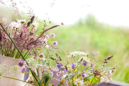 picked wild flowers with colorful flowers in a vase on a table decoratedの写真素材