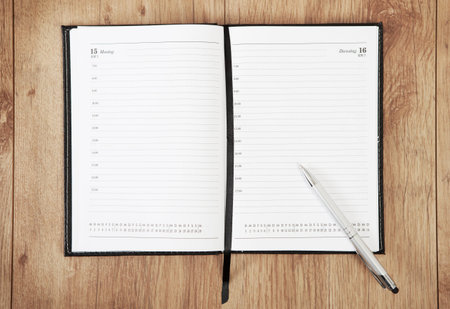 an unrecorded calendar with a pen lying on a wooden underground