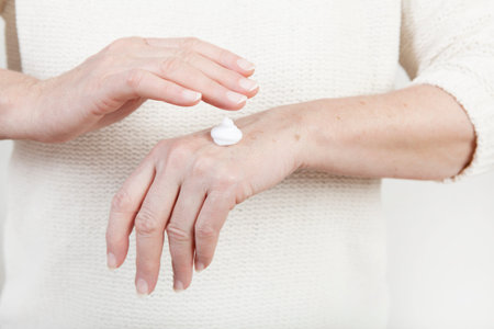 the hands of an elderly woman with hand cream