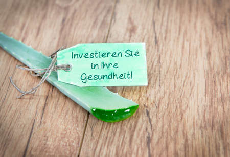 an aloe vera leaf with the text you invest in your health in germanの写真素材