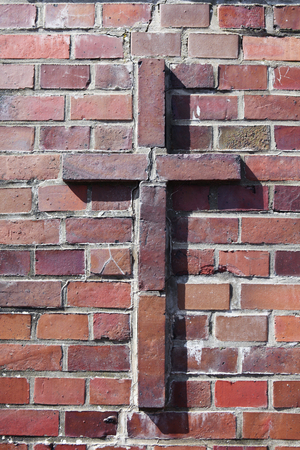 on an old church wall a cross of brick stonesの写真素材