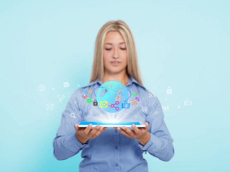 a young blond woman holds a tabletbook in her hands and surfs the internetの写真素材