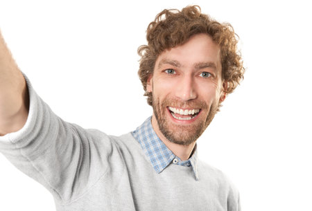 a young laughing man makes a selfi against a white backgroundの写真素材