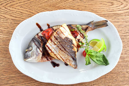 Fried Fish Dorado Garnished on Sliced Pumpkin with Basil Leaf and Sauceの写真素材