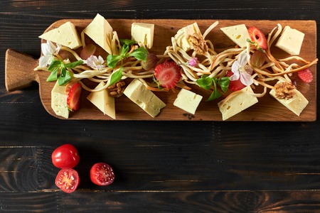 Pieces of cheese on a board with vegetables hdの写真素材