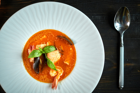 Homemade seafood soup with tomato sauce and coconut milk on an old wood trayの写真素材