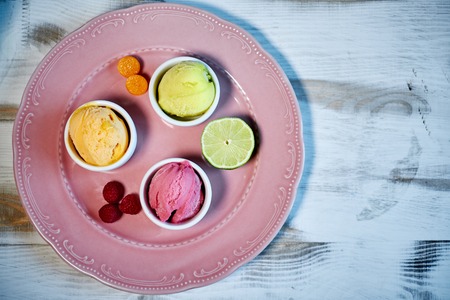 Selection of gourmet flavours of Italian ice cream in vibrant colors served in individual porcelain cups on an old rustic wooden table in an ice cream parlor, angle view jpgの写真素材