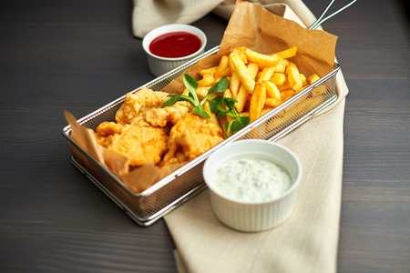 chicken nuggets with french fries and different sauces on wooden board,の写真素材