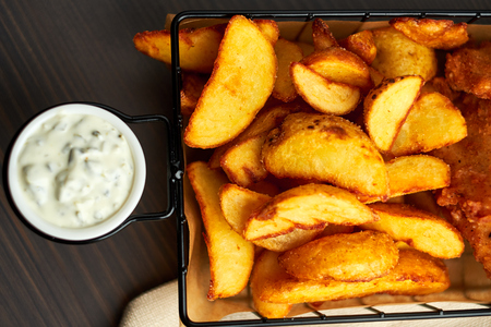 Nuggets and baked potatoes in a beautiful basket with white sauceの写真素材