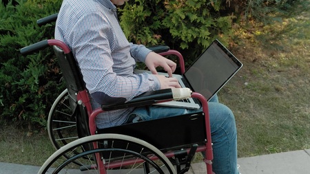 A disabled man in a wheelchair chair uses a virtual reality helmetの写真素材