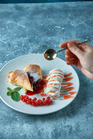Sliced homemade berry strudel served with fresh red currant berries and powdered sugar on an old...
