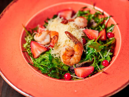 Fresh salad of arugula, shrimp and strawberry. Dark wooden background. Restaurant menuの写真素材