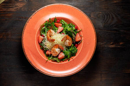 Fresh salad of arugula, shrimp and strawberry. Dark wooden background. Restaurant menuの写真素材
