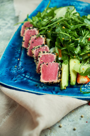 Tuna with salad and vegetables on blue plate