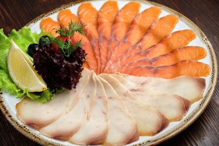 White and red fish sliced in thin slices on a brown wooden background. restaurant menuの写真素材