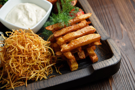 Hot appetizer on a wooden black plate on a dark wooden background. Restaurant menu