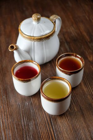 Different tea in teapots on a dark wooden background. catering menuの写真素材