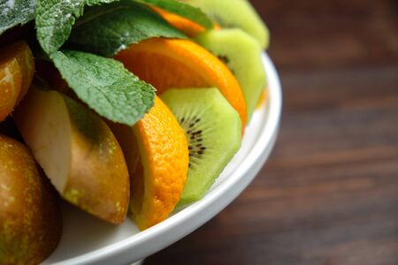 Sliced fruits on a white plate on a dark wooden background.の写真素材