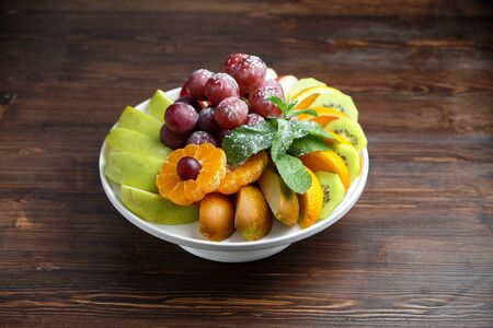 Sliced fruits on a white plate on a dark wooden background.の写真素材