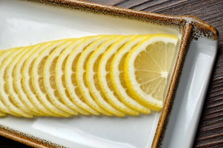 Thin sliced lemon on a brown wooden background. restaurant menuの写真素材