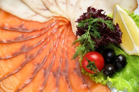 White and red fish sliced in thin slices on a white round plate in a beautiful serving on a brown rustic background. restaurant menuの写真素材