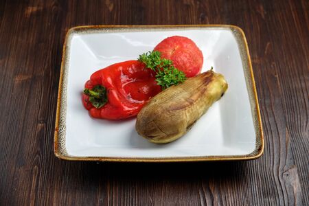 Grilled vegetables on a white plate on a dark wooden background. catering menuの写真素材